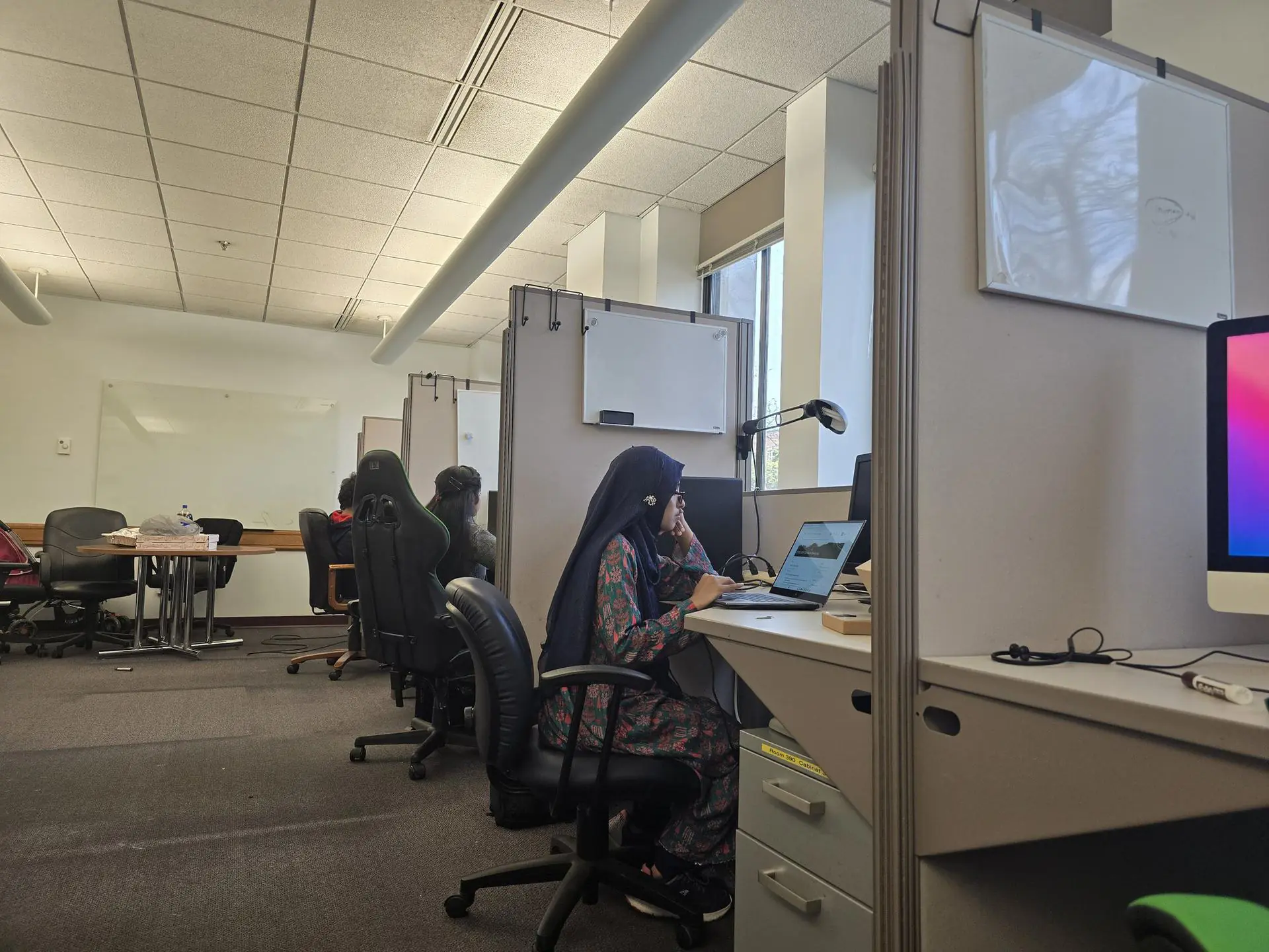 Researchers at shared workstations with computers and whiteboards in the Ubicomp Lab