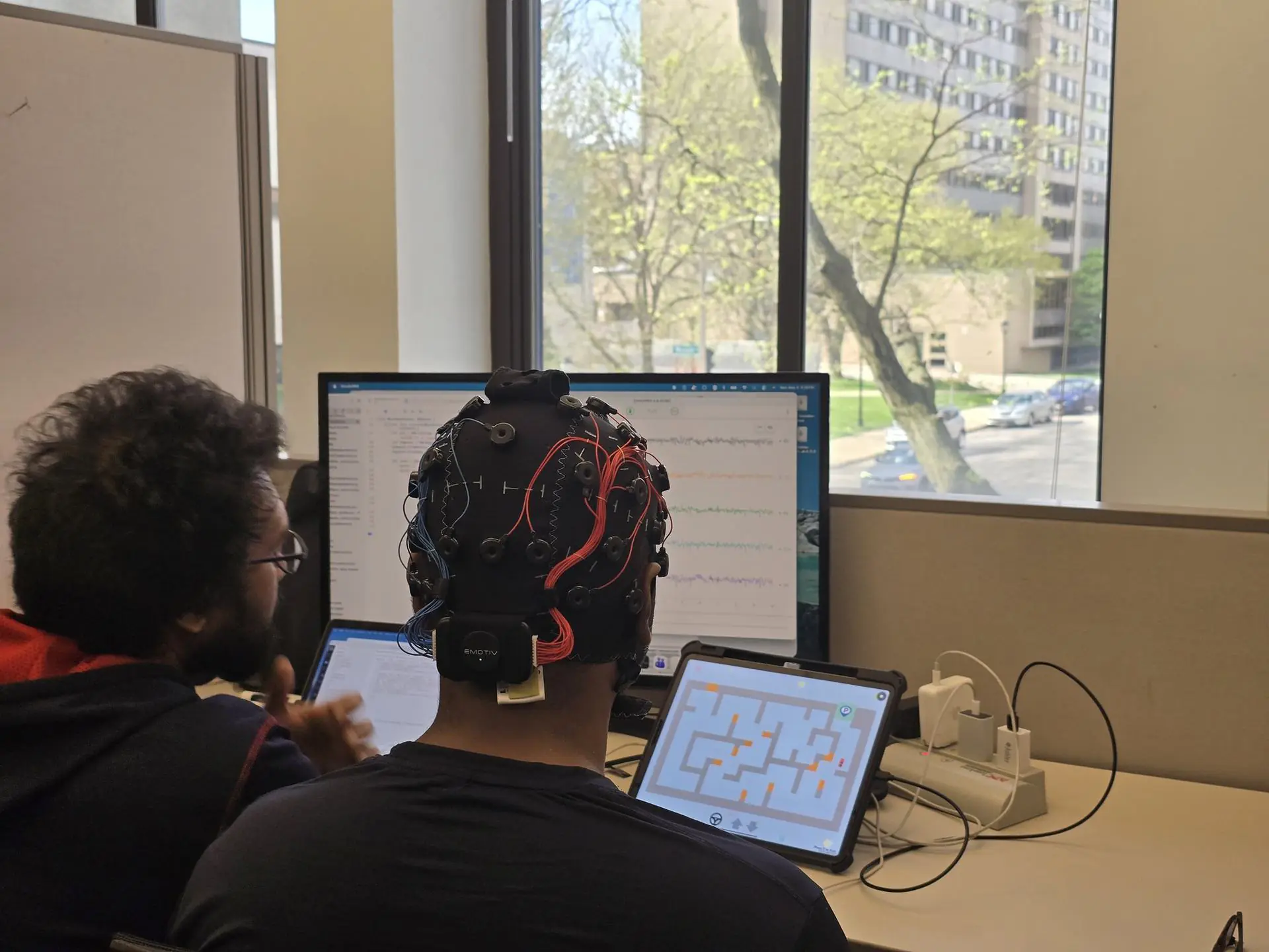 EMOTIV EEG headset, tablet, and live signal visualization on a monitor